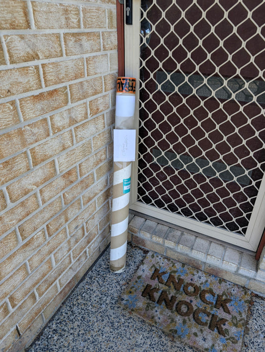 Rolled Elvis the Gang-gang Cockatoo print in a tube on a doorstep, ready for delivery.