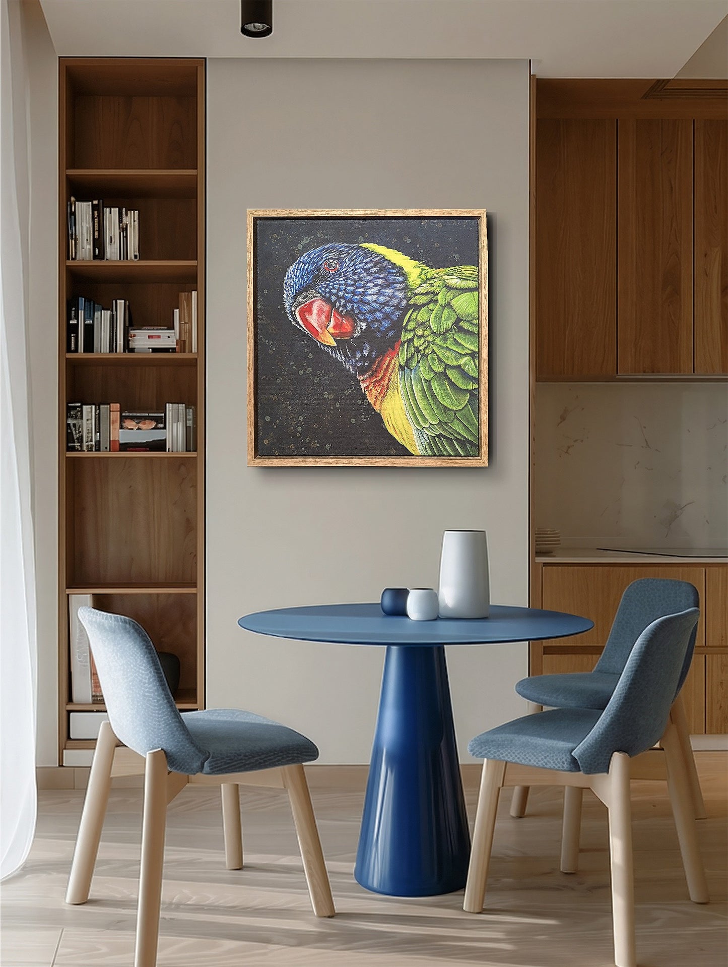 Modern interior with a blue dining table and chairs, bookshelf, and framed fine art reproduction print of Shazza the Rainbow Lorikeet by Kelly Batsiokis to show scale.