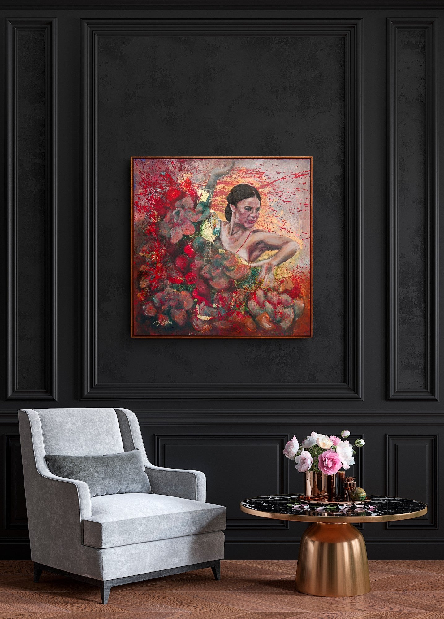 Framed abstract painting on a dark wall above a gray armchair with a small table and flowers.
