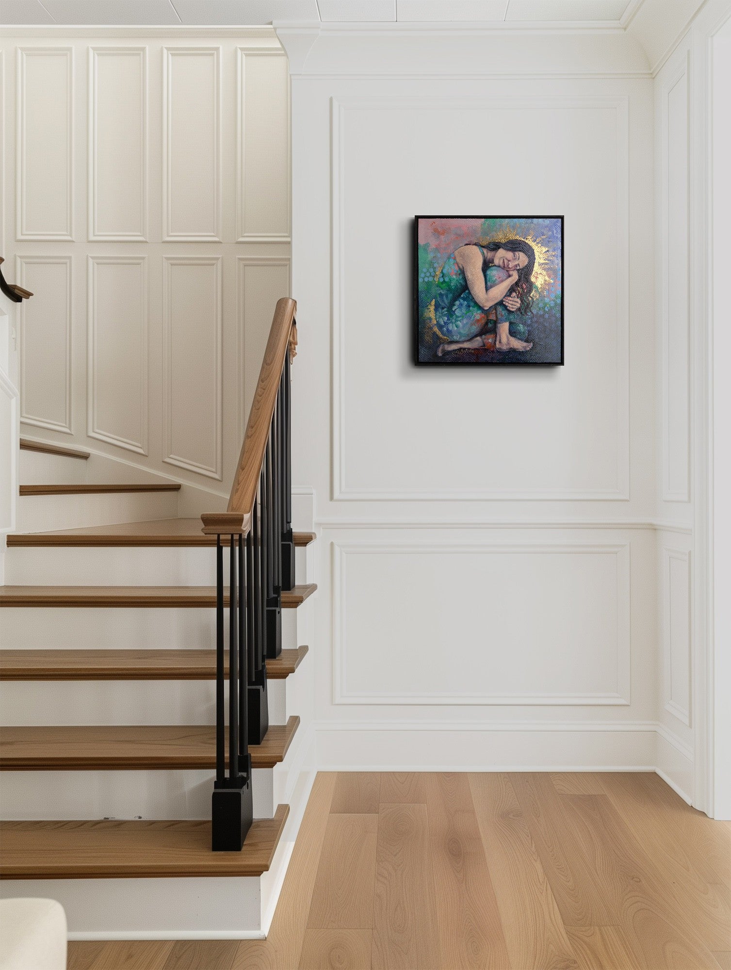 Staircase with wooden steps and black railing, wall art on a white paneled wall.