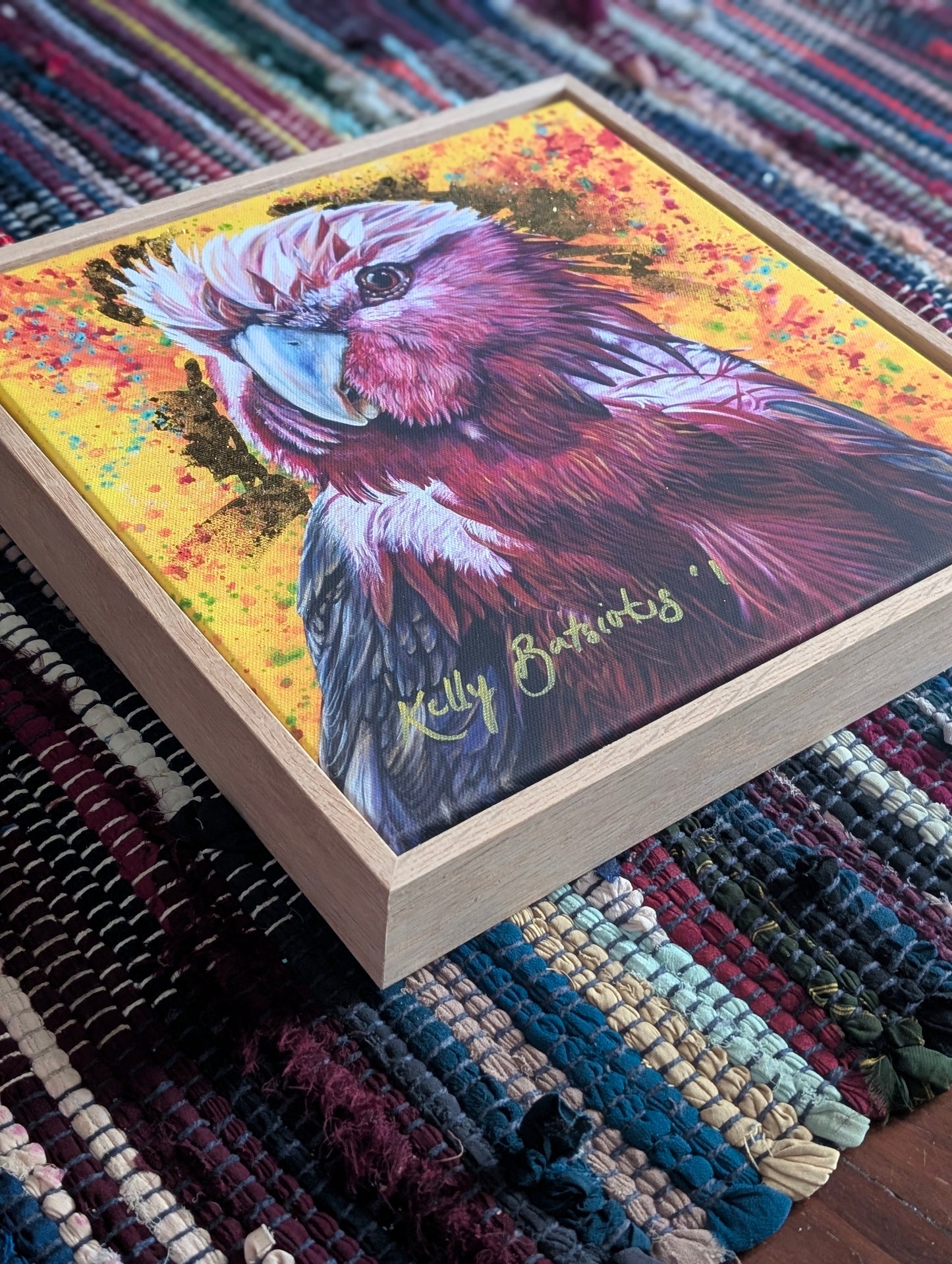 Embellished fine art print of Wally the Galah by Kelly Batsiokis on a textured fabric background showing frame quality.
