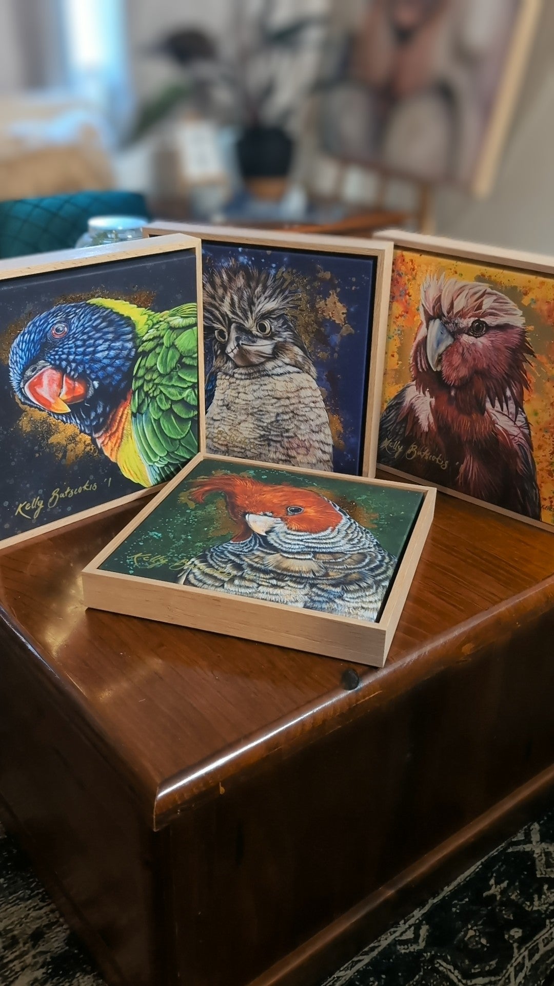 Set of bird-themed hand-embellished prints by Kelly Batsiokis on a wooden box on a wooden surface.