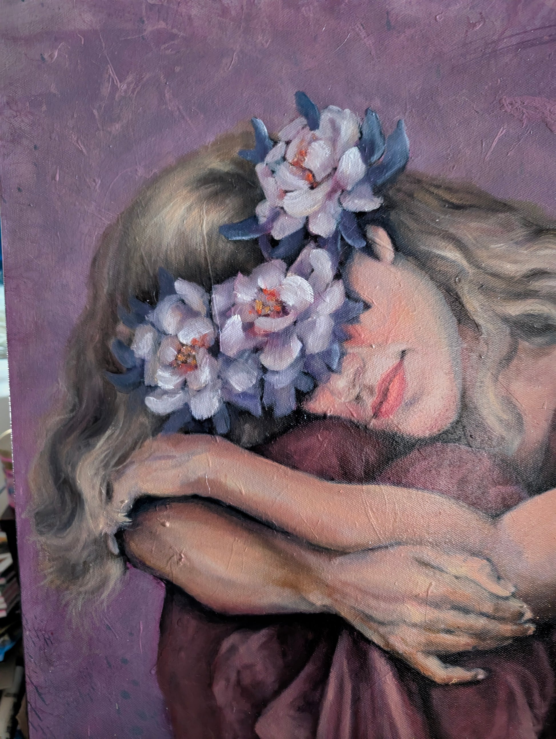 Close-up of Blooming Through the Night showing the woman’s face, flowers, folded arms and textured mixed media surface.