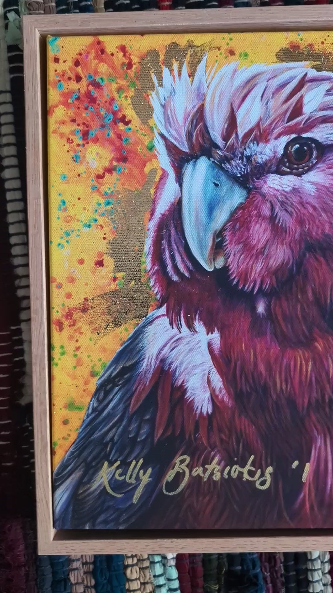 Video of Embellished fine art print of Wally the Galah by Kelly Batsiokis on a textured fabric background showing frame quality and sheen of gold-like foil.