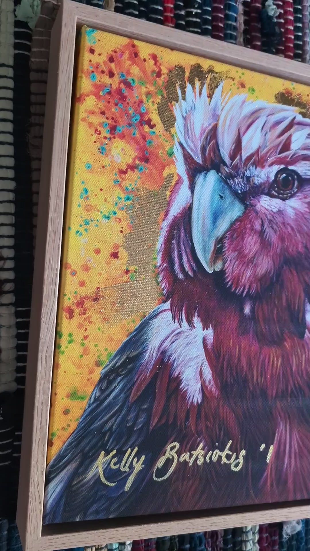 Video of Embellished fine art print of Wally the Galah by Kelly Batsiokis on a textured fabric background showing frame quality and sheen of gold-like foil.
